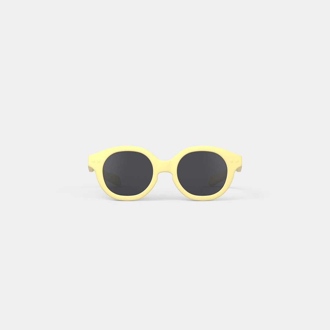 Yellow sunglasses with black lenses on a light gray background